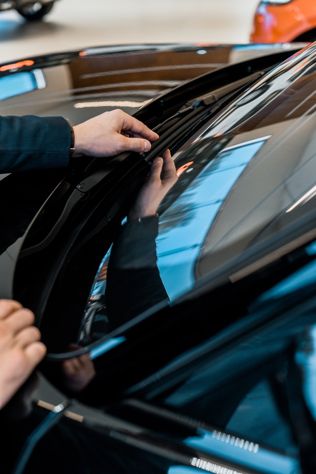 cropped image of businessman adjusting windshield wipers of black automobile